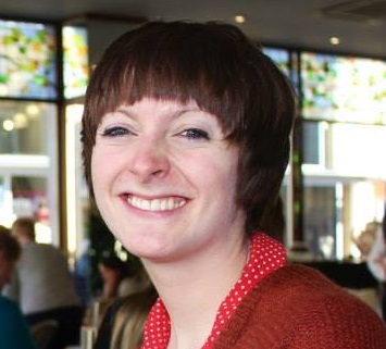 A woman with short brown hair, wearing a red top.