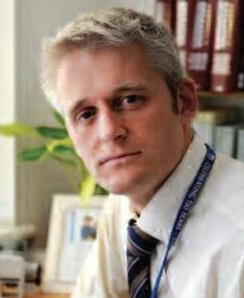 A man with blond hair, wearing a shirt and tie.