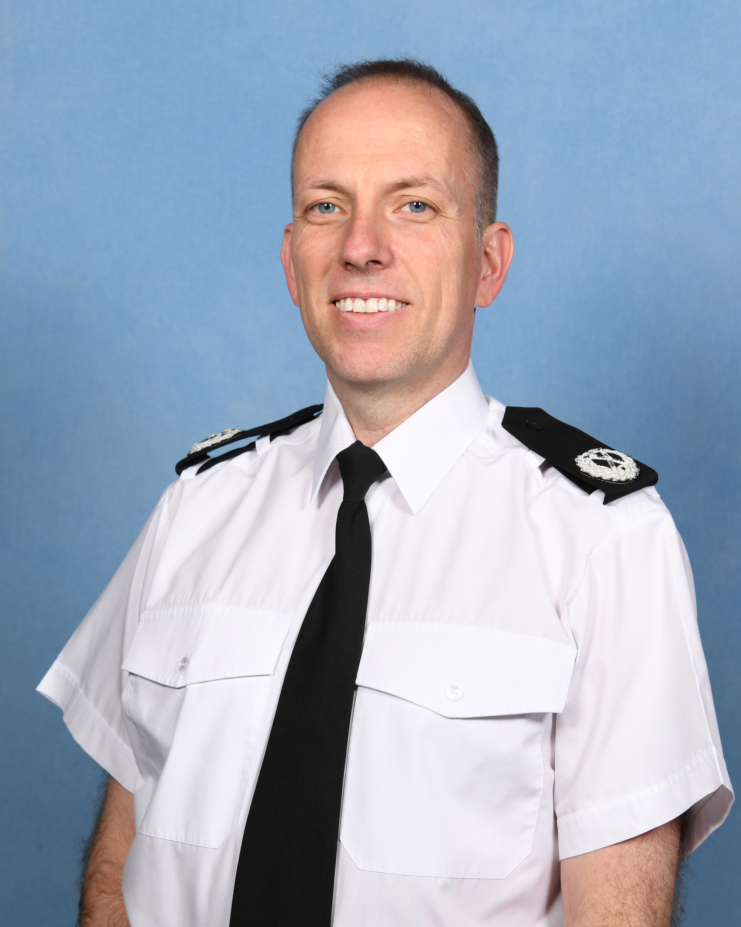A man smiling, wearing Police uniform