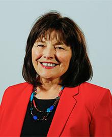 A woman with short dark hair, wearing a red suit jacket.