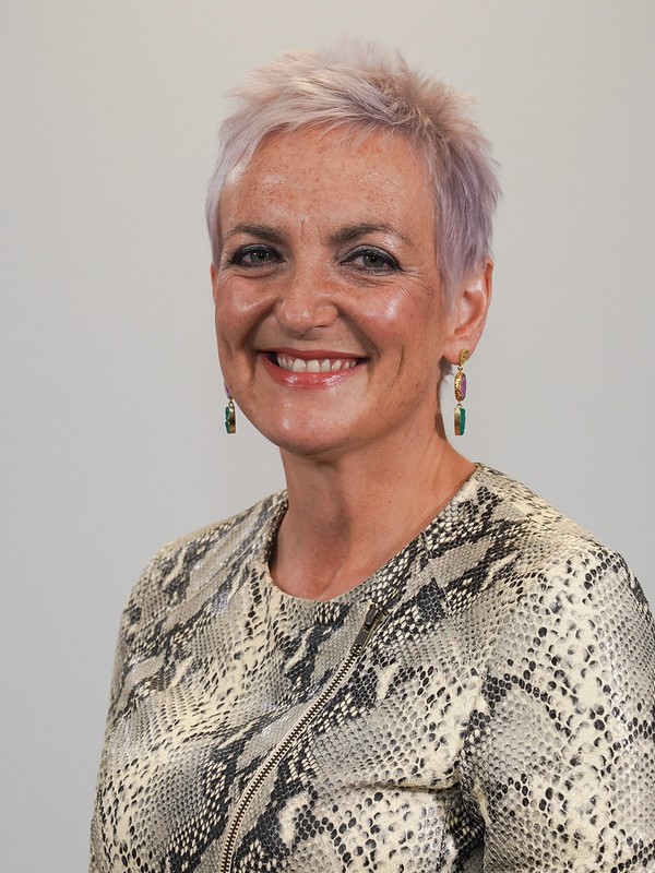 A woman with short blond hair, wearing a snakeskin print top.