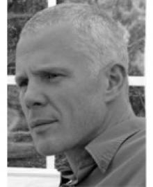 A black and white photo of a man with grey hair and a shirt on.