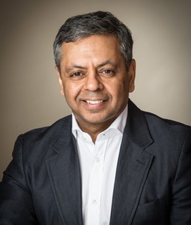 A man with dark hair, wearing a white shirt and black blazer.