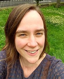 A woman with brown hair, wearing a purple top.