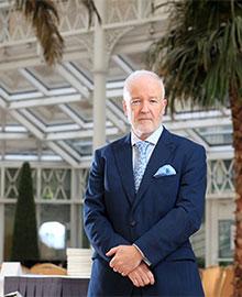 A grey haired man wearing a blue suit.