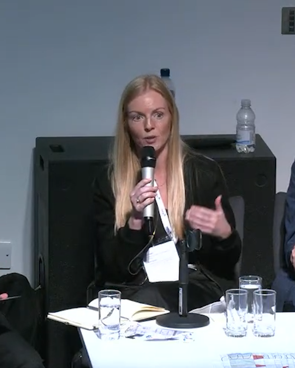 A woman speaking on a panel, holding a microphone