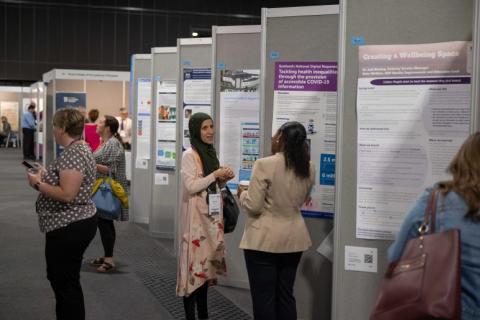 Women talking next to posters