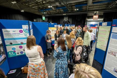 Image of people gathered around the posters in the exhibition space at the 2024 event