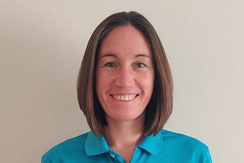 A woman with short brown hair, wearing a blue tshirt.