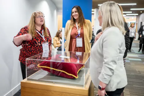 People discussing a cushion in a display case.