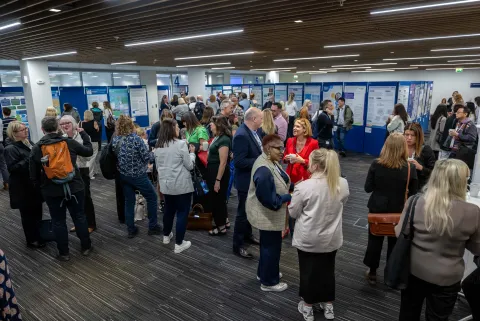 Many people talking amongst poster displays 