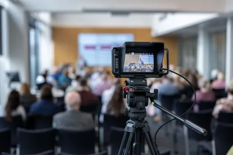 Looking though a camera screen at a people listening to a lecture.