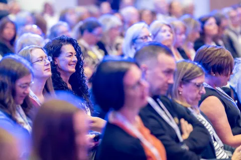 Audience members seated watching conference