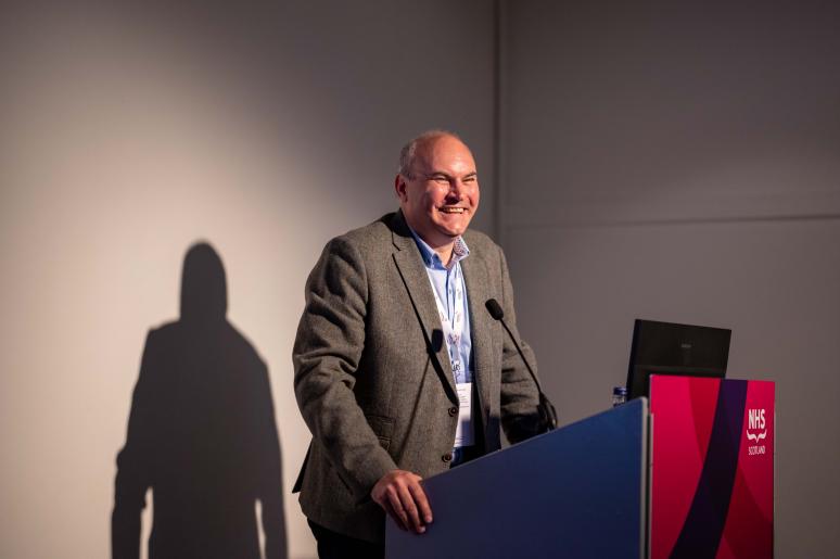 A speaker standing at a podium, giving a presentation