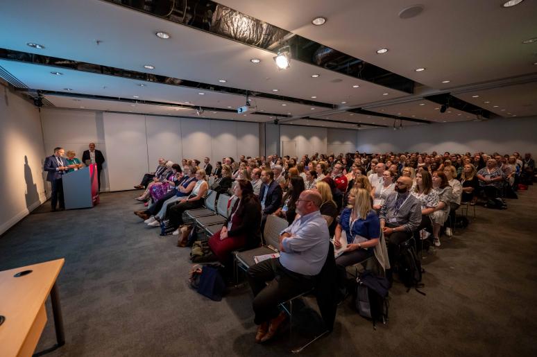 An event space with an audience sitting down, watching a presentation