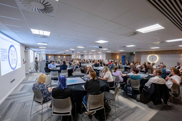 An event space with an audience sitting down, watching a presentation