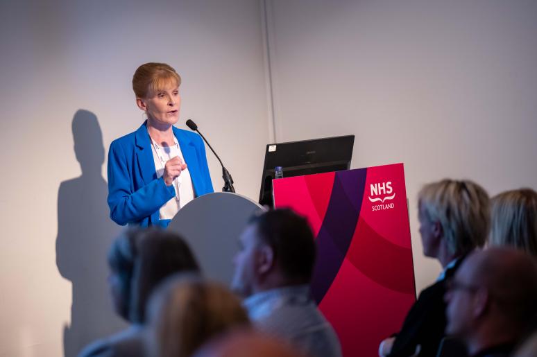 A speaker standing at a podium, giving a presentation