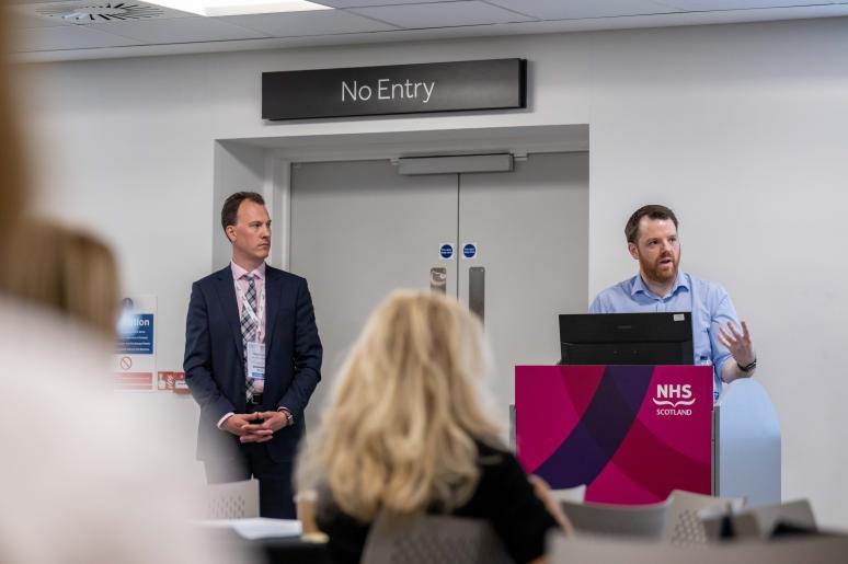 Two people standing at a podium, giving a presentation