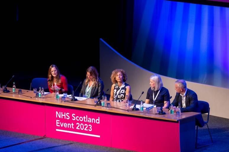 A panel of speakers sitting at a podium on the main stage