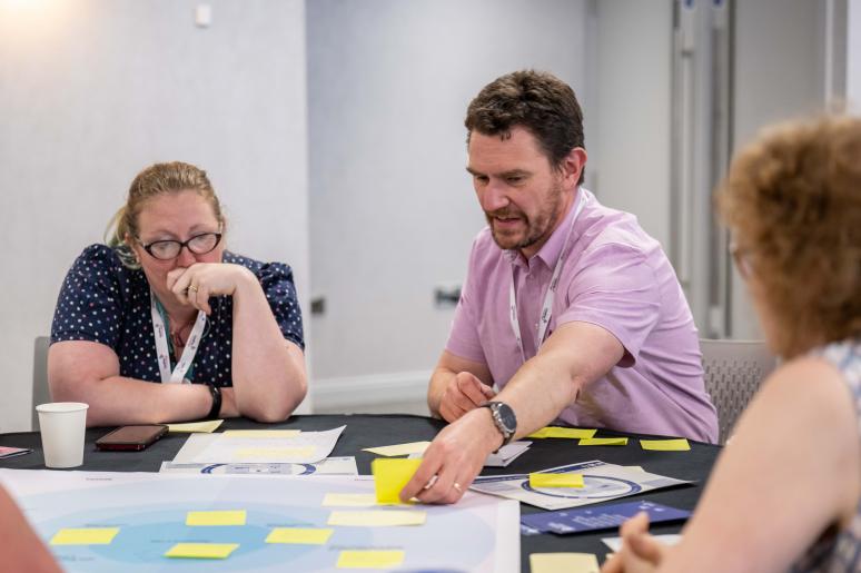 Three event attendees sitting at a table during a workshop