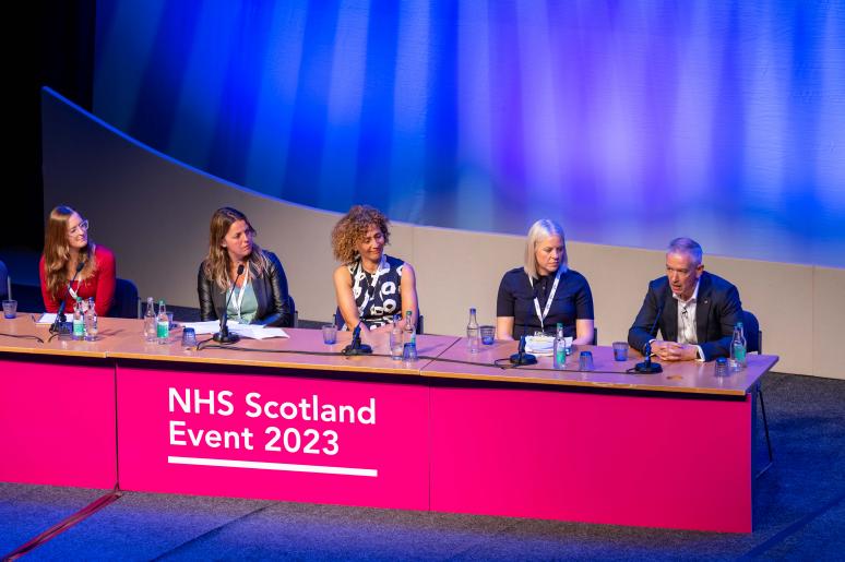 A panel of speakers sitting at a podium on the main stage