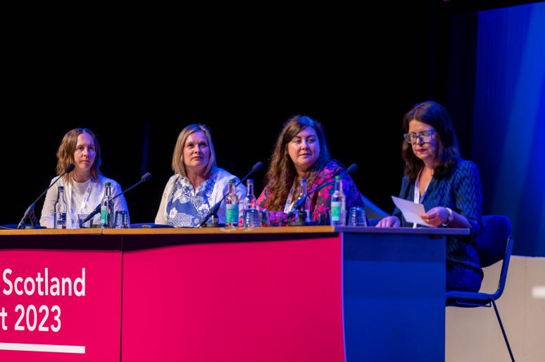 A panel of speakers sitting at a podium on the main stage