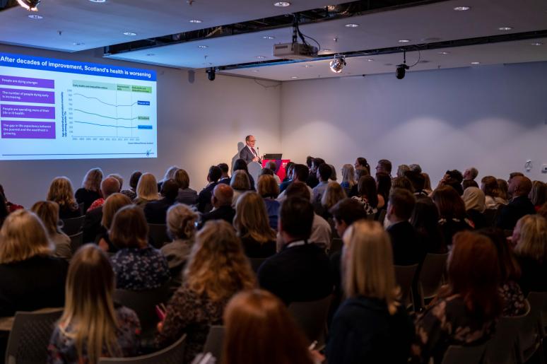 The main event space with event attendees watching a presentation